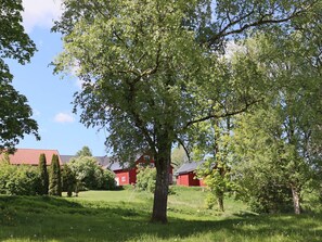 Un paisaje rural con un árbol grande, edificios rojos y un cielo despejado.