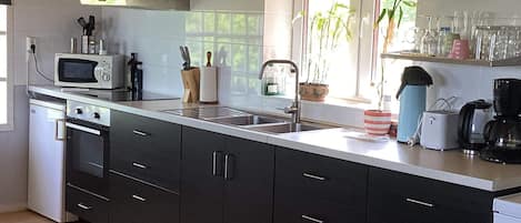 A modern kitchen with a microwave, oven, sink, and various appliances.