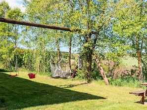A grassy outdoor area with trees, a swing, a picnic table, and a red bucket. - 4 Person Holiday Home in Ullared (Ullared)
