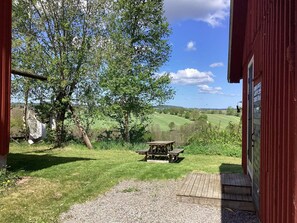 A wooden bench in a grassy area with a view of a red building and a tree. - 4 Person Holiday Home in Ullared (Ullared)