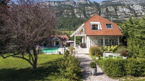 A house with a red-tiled roof, a covered patio, and a view of mountains. - Villa Mariette, large charming villa with lake view, swimming pool and large garden (Doussard)