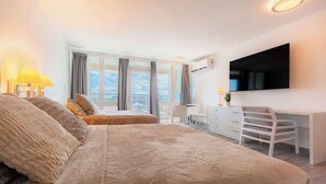 Habitación de hotel moderna con una cama grande, un escritorio, un televisor de pantalla plana y un balcón con vistas.