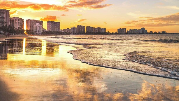 Una playa con el horizonte urbano al fondo.