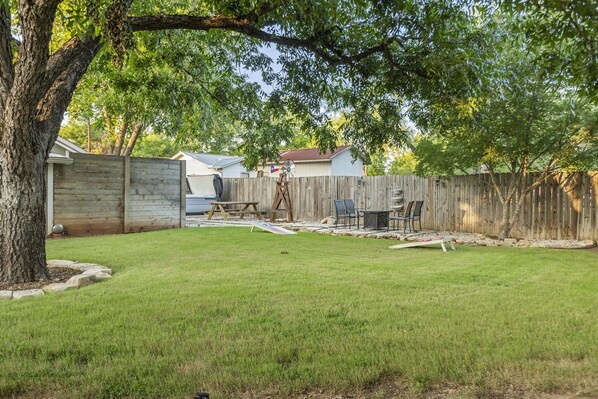 A backyard with a wooden fence, a picnic table, and a barbecue grill.
