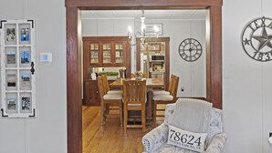 A dining area with a wooden table and chairs, a chandelier, and a clock on the wall. - 1929 Craftsman Charmer 2 Bedroom Home (Fredericksburg)
