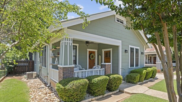 A single-story house with a covered porch, a brick fireplace, and a well-maintained lawn. - 1929 Craftsman Charmer 2 Bedroom Home (Fredericksburg)