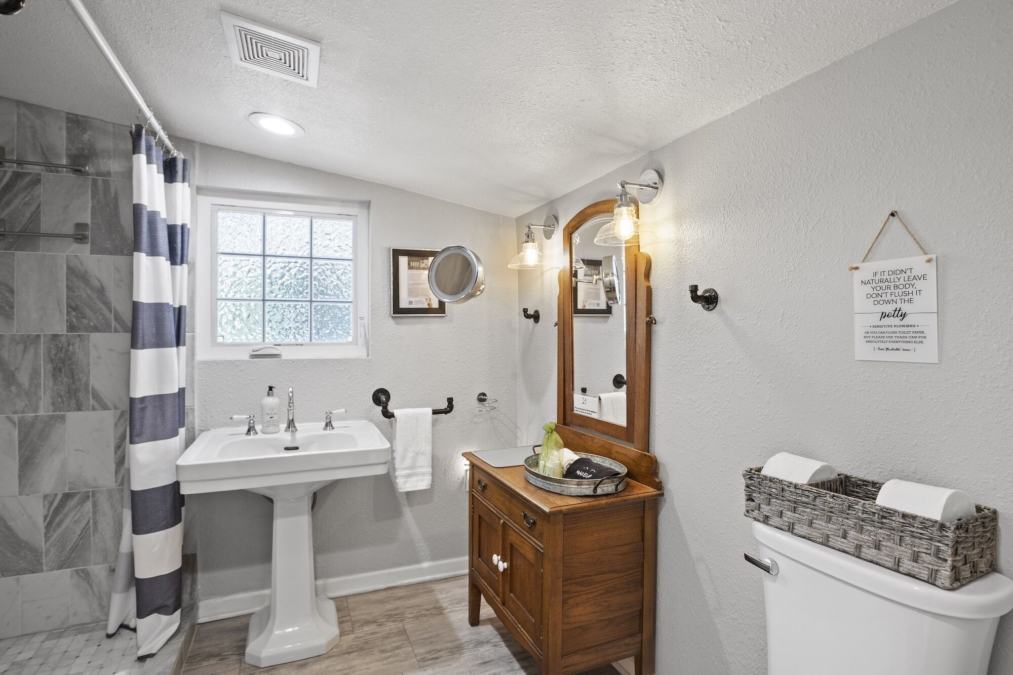 A bathroom with a white sink, wooden vanity, and a toilet.