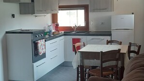 Una cocina compacta con armarios de madera, una mesa de comedor y un sofá en primer plano.