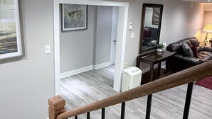 Un amplio salón con una escalera de madera, una mesa de comedor y un cómodo espacio de descanso.