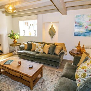 A cozy living room with a green sofa, a wooden coffee table, and a patterned rug.