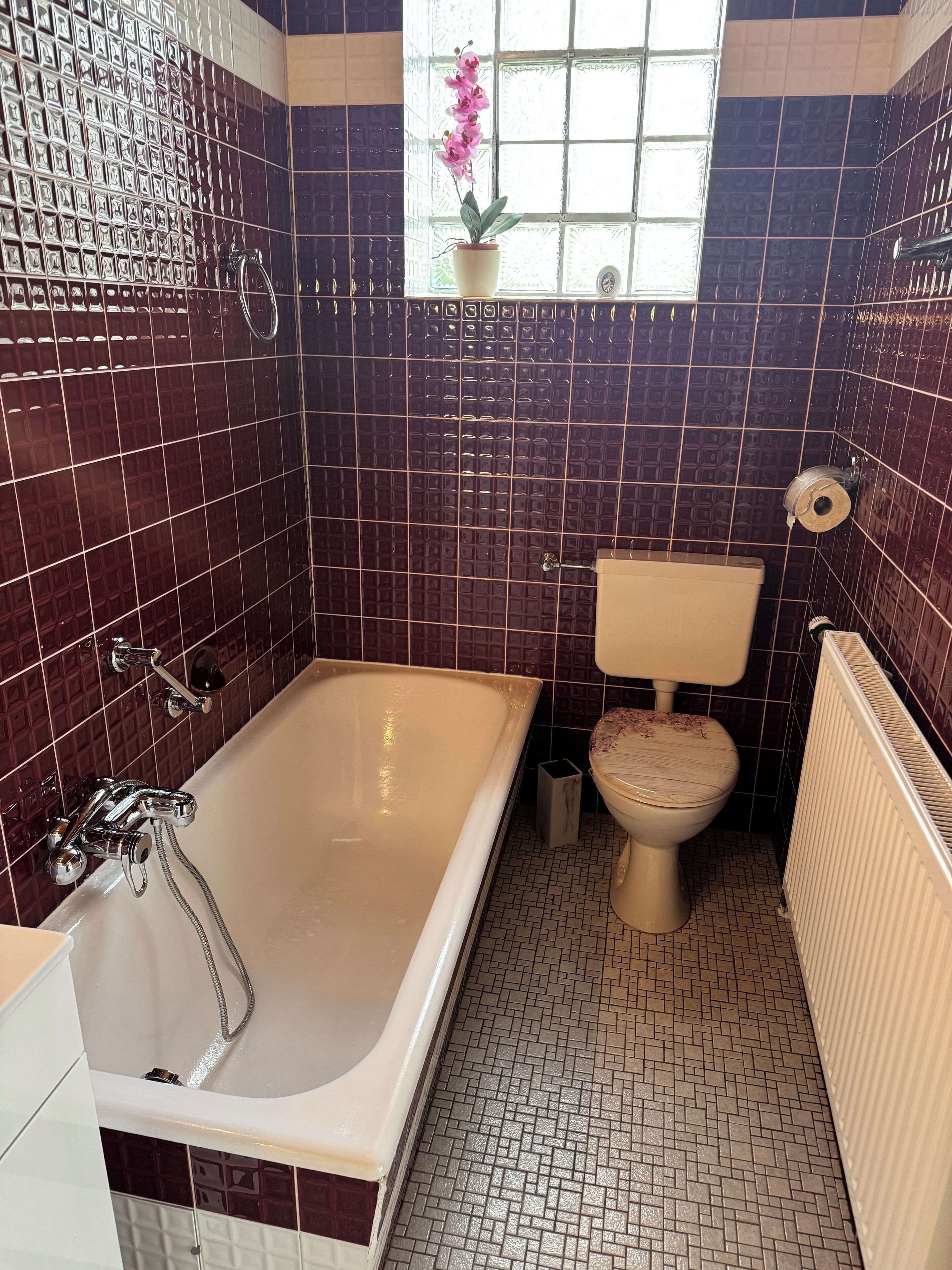 Un bagno con vasca, servizi igienici e una finestra con un'orchidea in vaso.