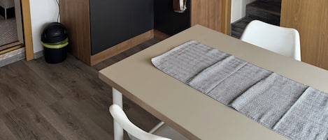 Eine kompakte Küche mit Holzarbeitsplatte, Spüle und einem kleinen Schrank. Vorhanden ist ein Esstisch mit einem Stuhl.