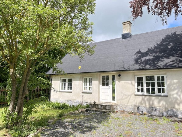 A single-story house with a grey roof, white exterior walls, and a front door. - 5 Star Holiday Home in Hammenhog (Hammenhög)