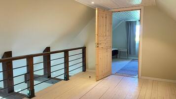 Una habitación con escalera de madera, una puerta que da a otra estancia y un banco a la vista.