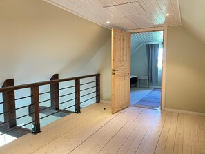 A room with a wooden staircase, a door leading to another room, and a visible bench.