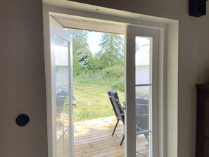 A door leading to an outdoor deck with a chair and a table.