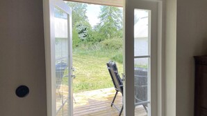 A view through a glass door into a backyard with a wooden deck, a lawn, and a patio chair. - 5 Star Holiday Home in Hammenhog (Hammenhög)