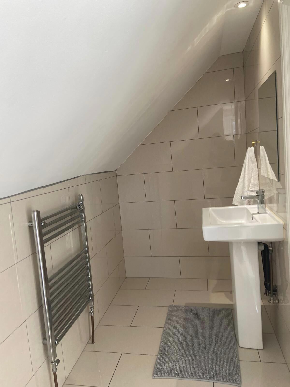 Une salle de bain moderne avec une douche à parois de verre, un lavabo blanc et un porte-serviettes.