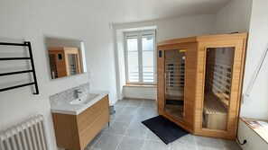 Une salle de bain moderne avec un lavabo blanc, des meubles en bois, une serviette noire et une grande fenêtre.
