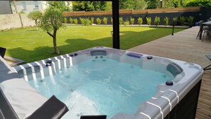 Un jacuzzi con un muelle de madera y un césped al fondo.