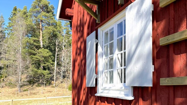 A red wooden cabin with white shutters, a window, and a wooden deck. - 4 Star Holiday Home in Sandhem (Mullsjö)