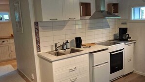 Une cuisine compacte avec des meubles blancs, un four encastré et une fenêtre qui laisse entrer la lumière naturelle.