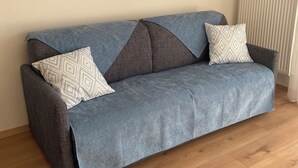 A grey sofa with patterned cushions, a framed artwork above, and a radiator to the right. - AZUR Rated 3 stars (Camiers)