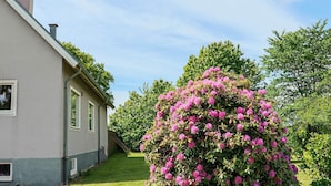 Une maison avec un toit en pente, une cheminée bien visible et une pelouse bien entretenue.