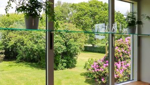 Une pièce dotée d’une grande fenêtre, d’un banc en bois et d’une plante en pot posée sur le rebord de la fenêtre.