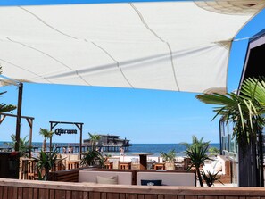 Ein Restaurant direkt am Strand mit Terrassenplätzen, Meerblick und einer Holzterrasse.
