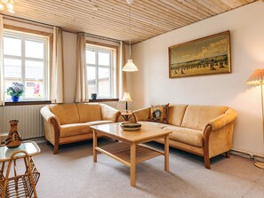 A cozy living room with a sofa, a coffee table, and a painting on the wall.