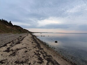 Ein Strand mit einem klaren Weg zum Wasser, umgeben von Hügeln.