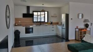 A modern kitchen with a central island, built-in oven, and a refrigerator. - Maison Noé ( New Villa ) Spacious near the center Fully air-conditioned (Ruoms)