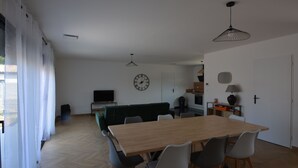 A spacious living area with a wooden dining table, modern chairs, a green sofa, and a kitchen in the background. - Maison Noé ( New Villa ) Spacious near the center Fully air-conditioned (Ruoms)
