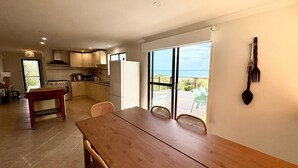 Una cocina con comedor, vista al océano y puerta corrediza de vidrio.