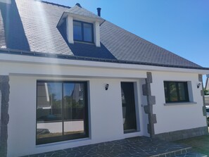 A modern house with a sloped roof, large windows, and a stone foundation.