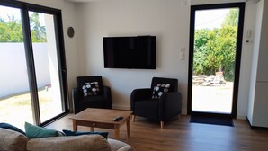 A modern living room with a sofa, two armchairs, a coffee table, and a TV mounted on the wall. - Quiberonnaise house in town center, walking distance to beach. (Quiberon)