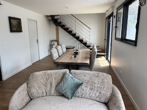 A modern living room with a sofa, a dining table, and a staircase leading to another level. - House in the center of Quiberon, within walking distance of the beach (Quiberon)
