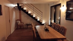 A dining area with a wooden table and benches, a staircase, and a chair with a cushion. - Quiberonnaise house in town center, walking distance to beach. (Quiberon)