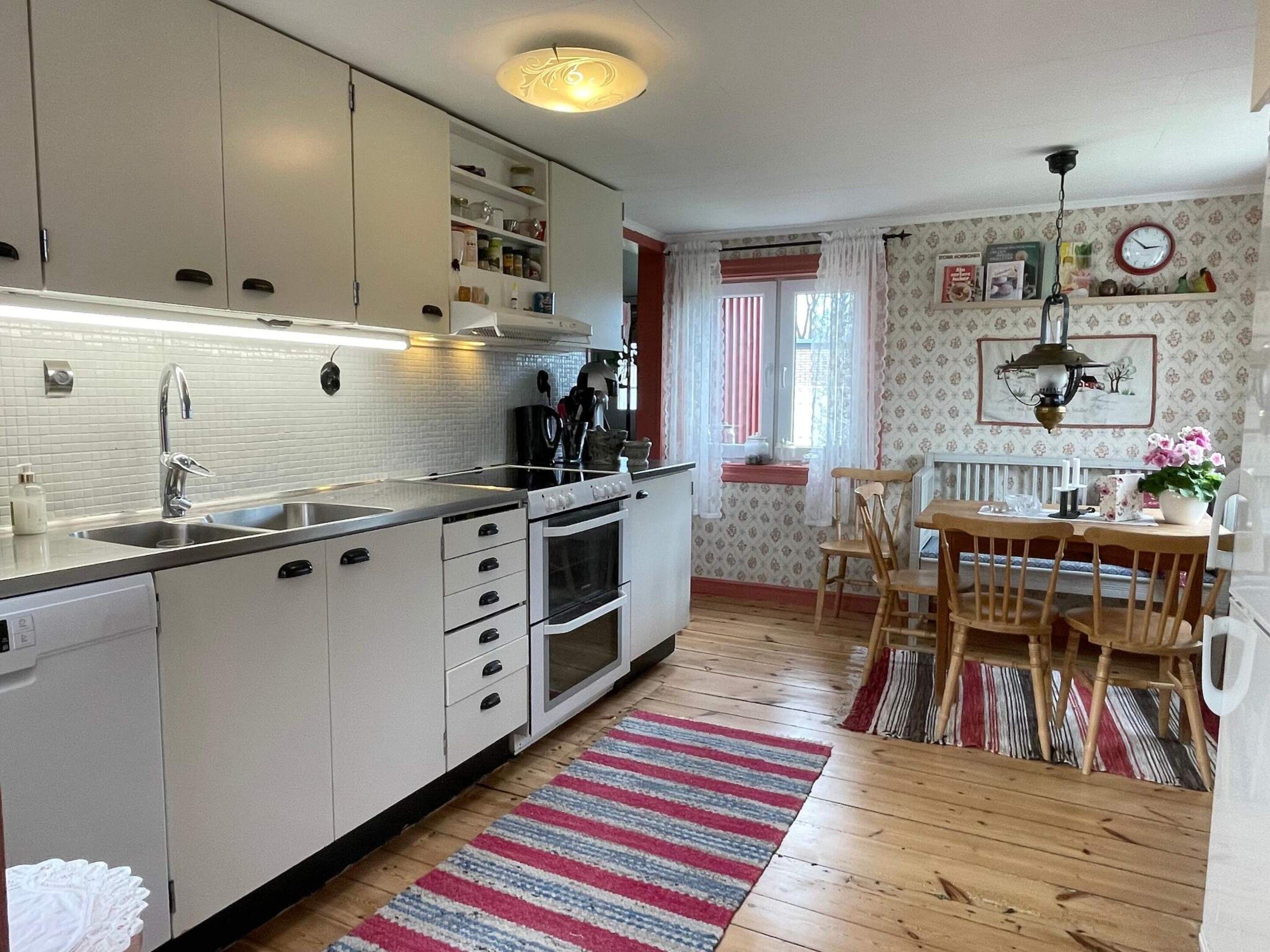 A kitchen with white cabinets, a stove, and a dining area with a table and chairs.
