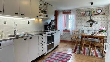 A kitchen with white cabinets, a stove, and a dining area with a table and chairs.