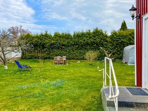 A well-maintained garden with a lawn, a wooden table and chairs, and a blue lawn chair. - 4 Person Holiday Home in Vastervik (Vastervik)
