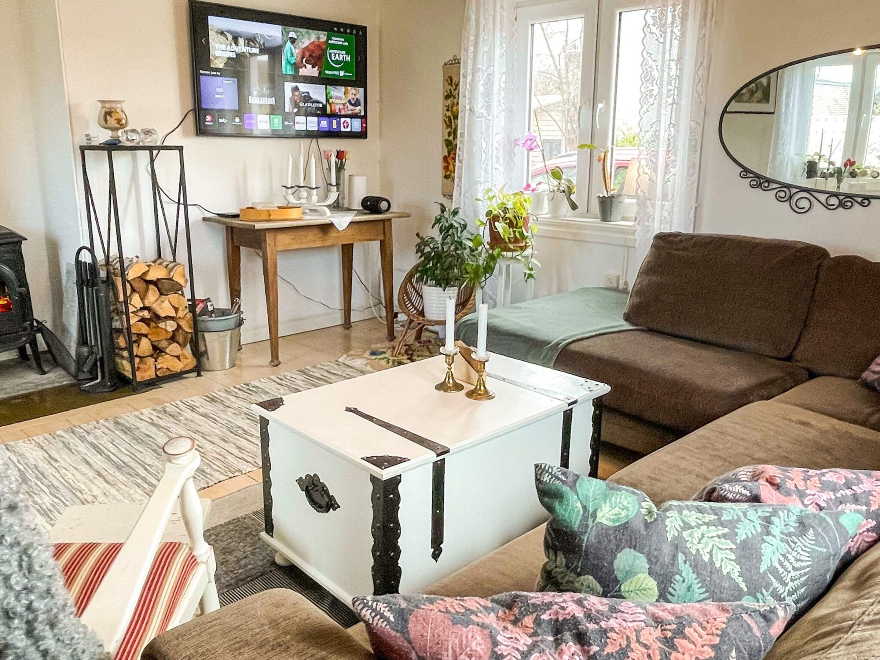 A living room with a sofa, a white coffee table, a television mounted on the wall, and a fireplace.