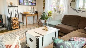A living room with a sofa, a white coffee table, a television mounted on the wall, and a fireplace.