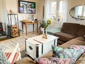 Una sala de estar con un sofá, una mesa de centro blanca, un televisor montado en la pared y una chimenea.