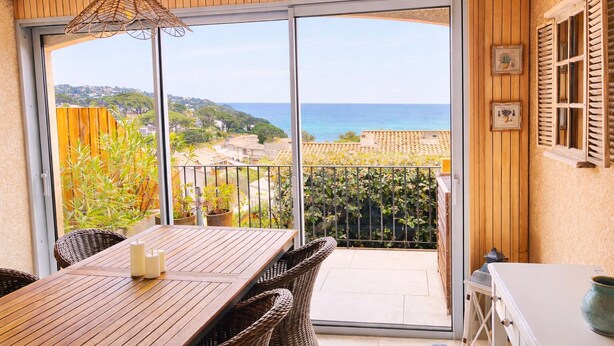 A balcony with a view of the sea, a table with chairs, and a hanging light fixture. - Incredible sea view-beach 300m away-pool-parking-fully renovated-2 bedrooms (Sainte-Maxime)
