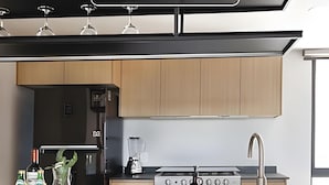 Ett modernt kök med träskåp, en gasspis, en mixer och vinglas på bänkskivan.