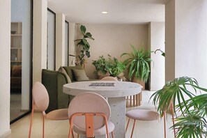Una sala de estar moderna con una mesa redonda, dos sillas, un sofá y varias plantas en macetas.
