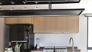 A modern kitchen with wooden cabinets, a gas stove, a blender, and wine glasses on the countertop.