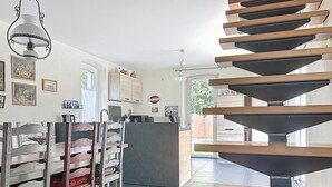 Ett modernt kök med en central köksö, trästolar och en spiraltrappa.